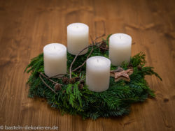 Adventzkranz aus Tannenzweigen und Thujazweigen. Dekoriert mit weißen Kerzen, kleinen Zapfen und Holzsternen. Es wurden nur Naturmaterialien verwendet.